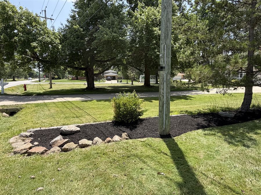 Long fresh mulch bed with a stone border by the road